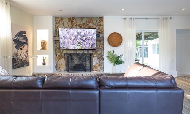 living room featuring a stone fireplace and hardwood / wood-style flooring