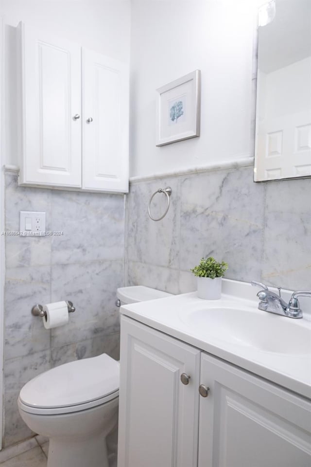 bathroom featuring vanity, toilet, and tile walls