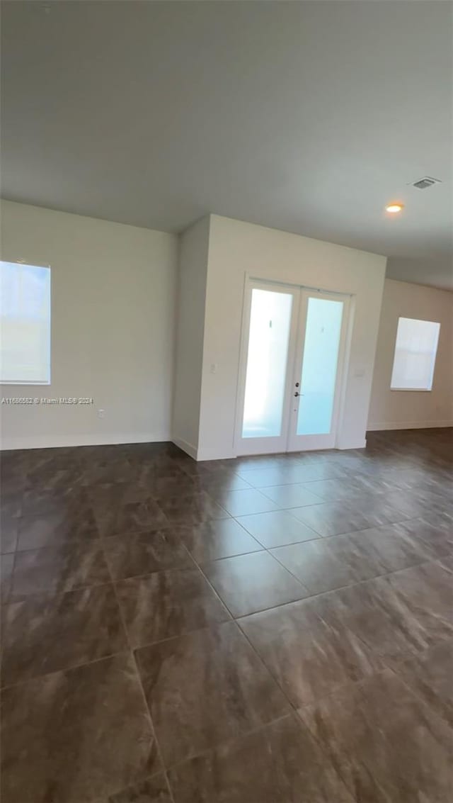 tiled spare room featuring french doors