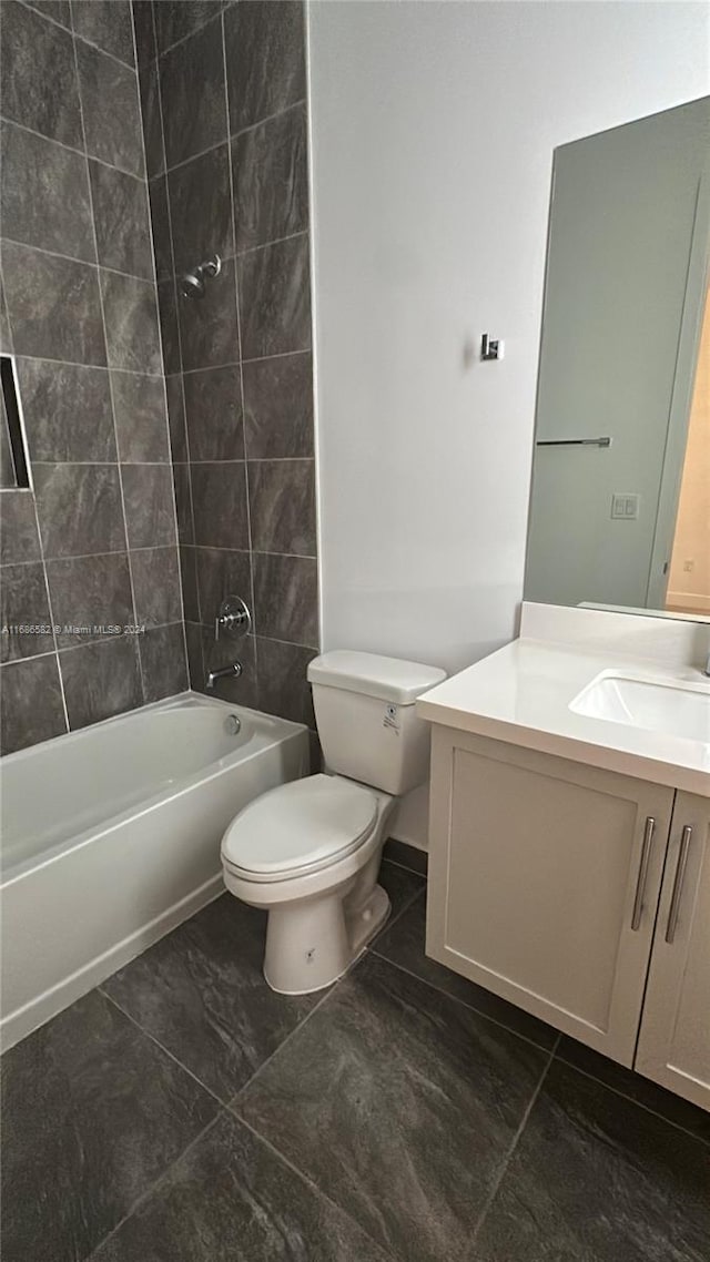 full bathroom featuring tiled shower / bath, vanity, toilet, and tile patterned flooring