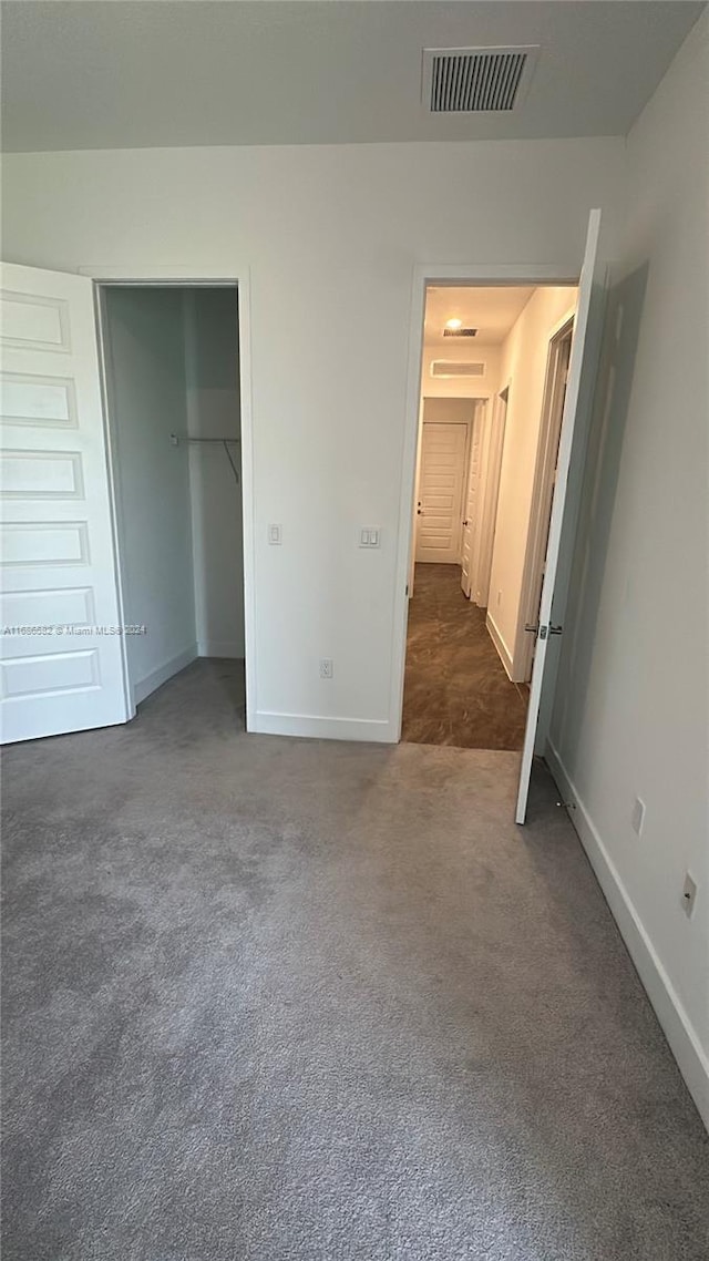 unfurnished bedroom with dark colored carpet and a closet