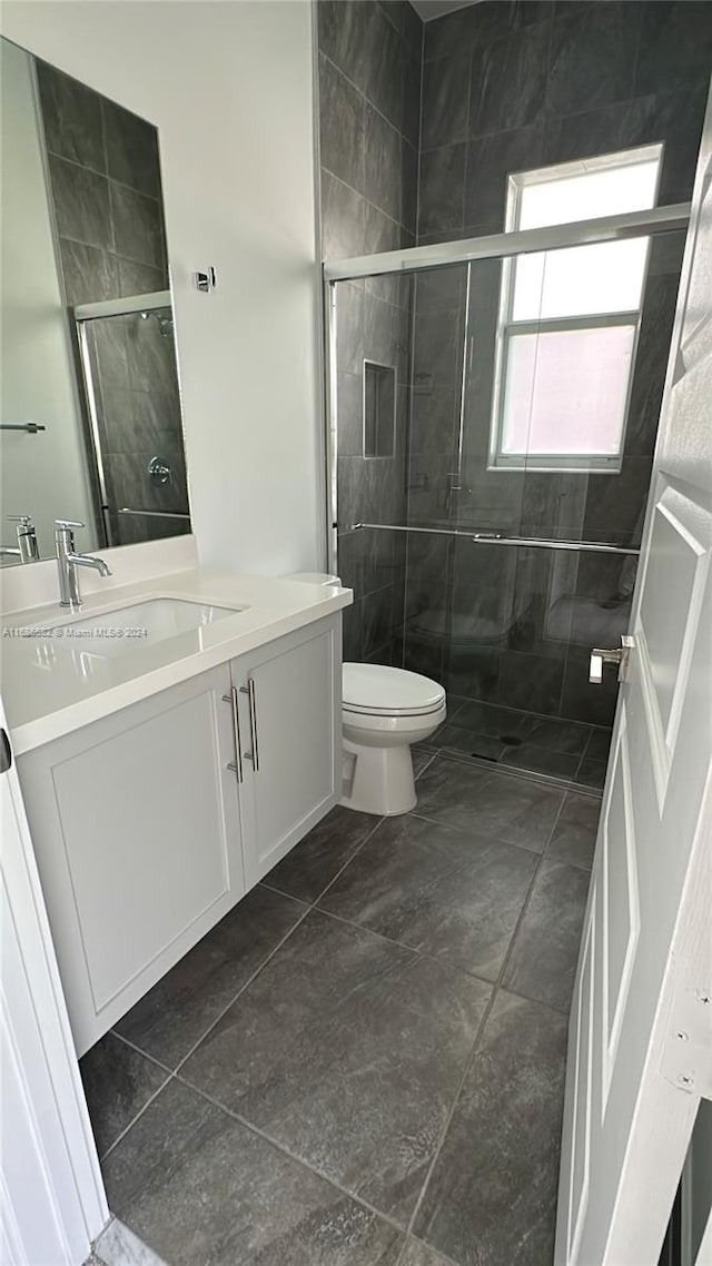 bathroom with vanity, toilet, walk in shower, and tile patterned flooring