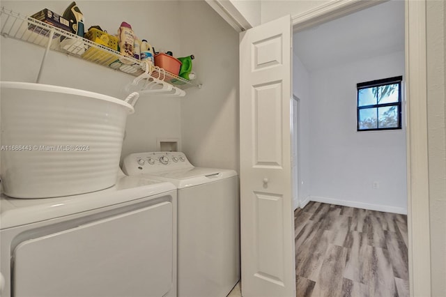 clothes washing area with independent washer and dryer and light hardwood / wood-style flooring