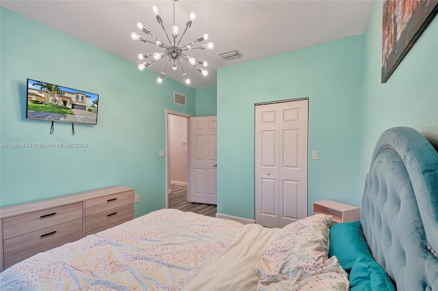 bedroom with a closet, wood-type flooring, and an inviting chandelier