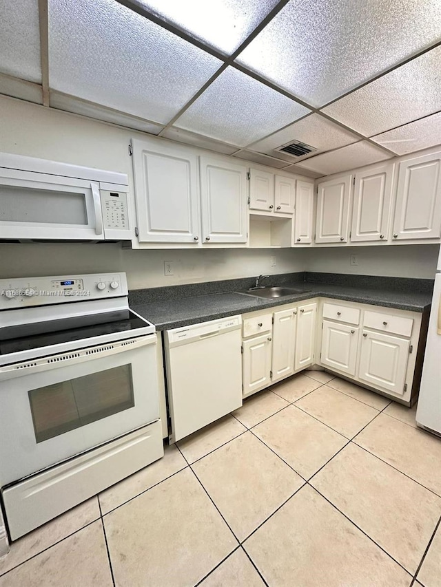 kitchen with sink, a drop ceiling, light tile patterned floors, white cabinetry, and white appliances