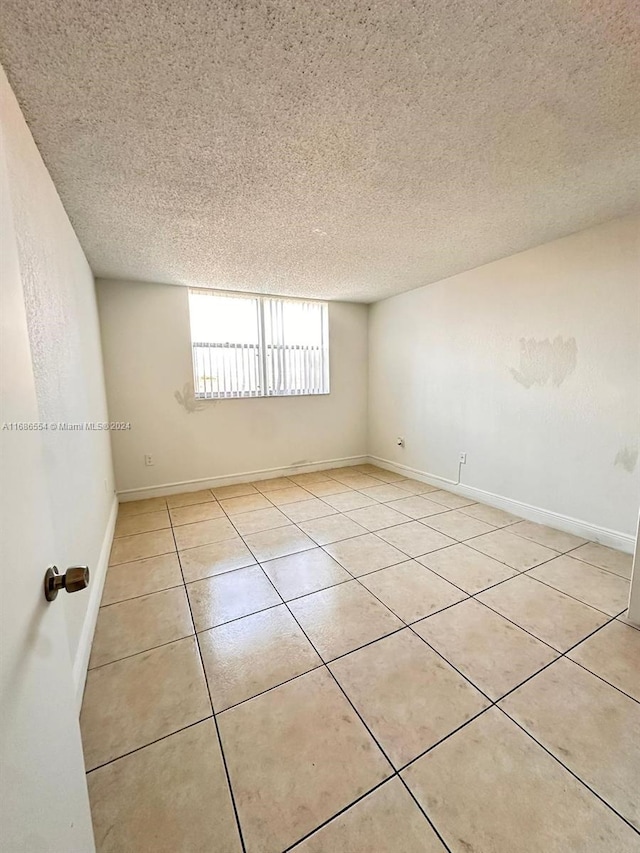 spare room with a textured ceiling and light tile patterned flooring