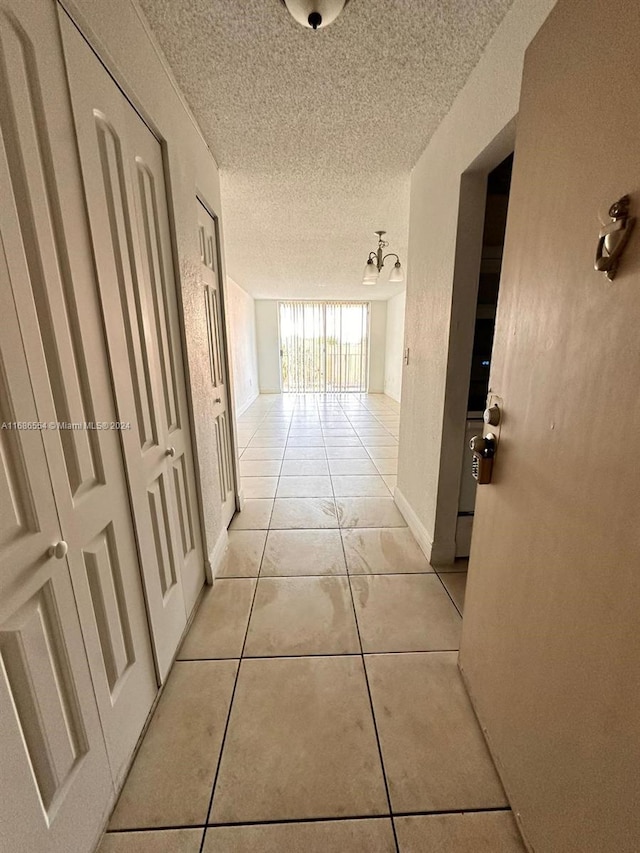 hall featuring a textured ceiling and light tile patterned floors