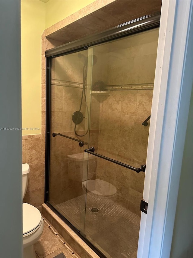 bathroom featuring toilet and a shower with shower door