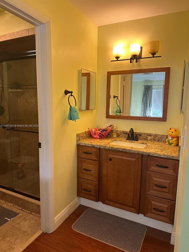 bathroom with vanity, a shower with shower door, and hardwood / wood-style floors