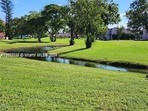 view of property's community featuring a lawn and a water view