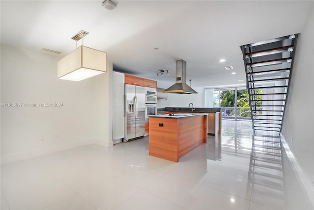 kitchen with island exhaust hood, a kitchen island, appliances with stainless steel finishes, light tile patterned flooring, and decorative light fixtures