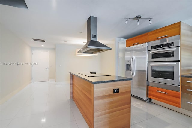 kitchen with appliances with stainless steel finishes, island exhaust hood, light tile patterned floors, and a kitchen island