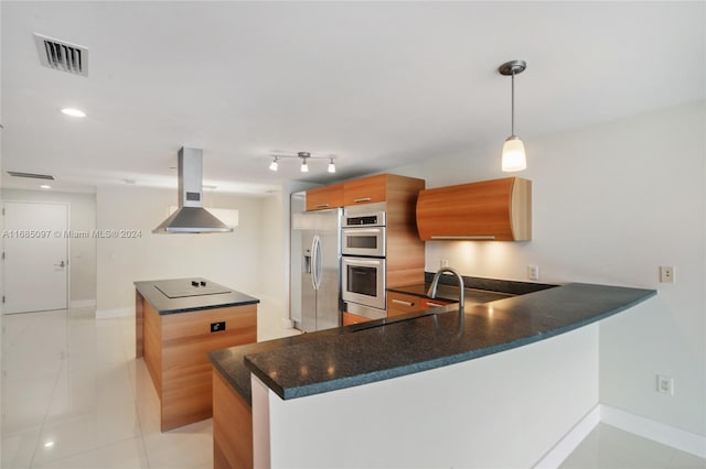 kitchen with kitchen peninsula, appliances with stainless steel finishes, island range hood, light tile patterned flooring, and decorative light fixtures