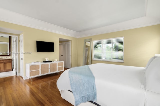 bedroom with connected bathroom, crown molding, and dark hardwood / wood-style flooring