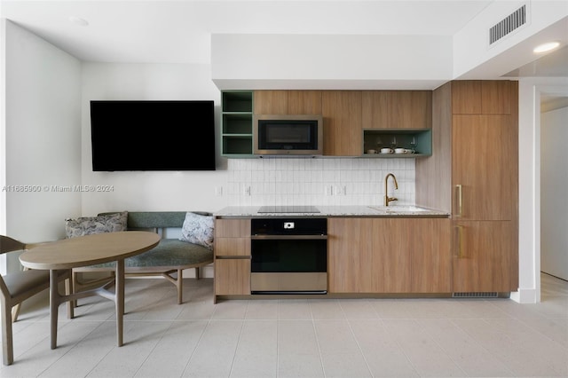 kitchen featuring light stone countertops, sink, appliances with stainless steel finishes, and backsplash