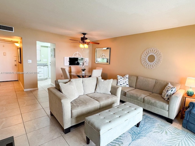 living room with a textured ceiling, light tile patterned floors, and ceiling fan