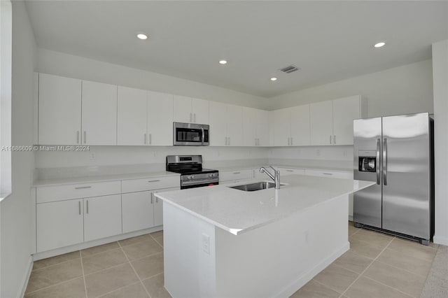 kitchen with a center island with sink, sink, light tile patterned floors, white cabinetry, and appliances with stainless steel finishes