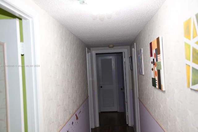 corridor with a textured ceiling and hardwood / wood-style flooring