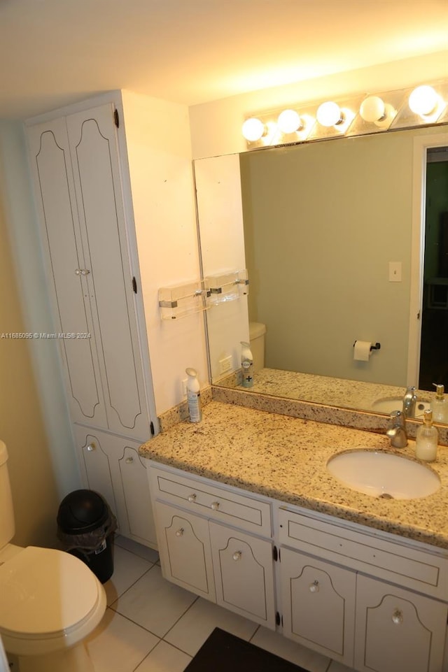 bathroom with toilet, vanity, and tile patterned floors