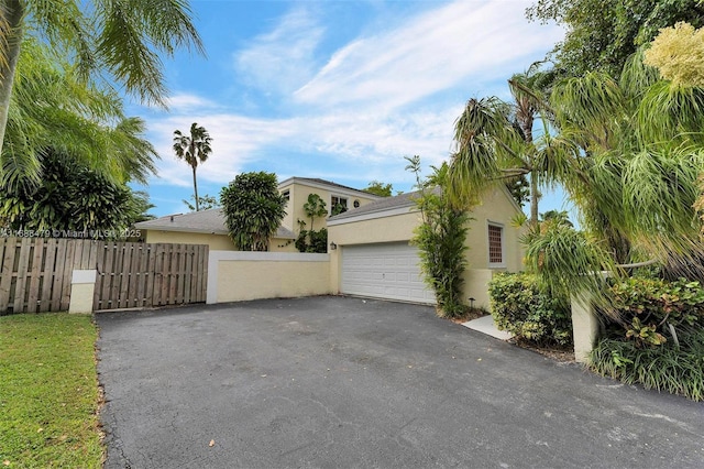 garage featuring fence and aphalt driveway