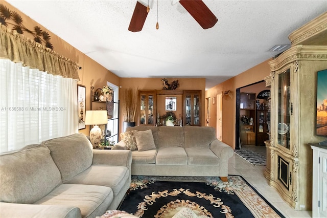 living room featuring a fireplace, a textured ceiling, and ceiling fan