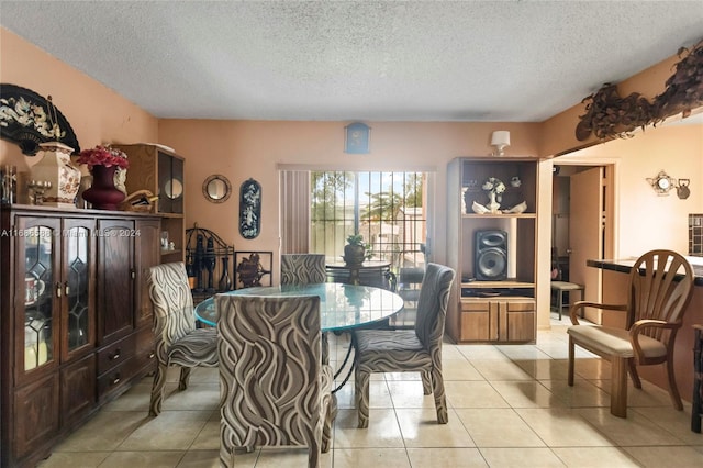 dining space featuring light tile patterned flooring and a textured ceiling