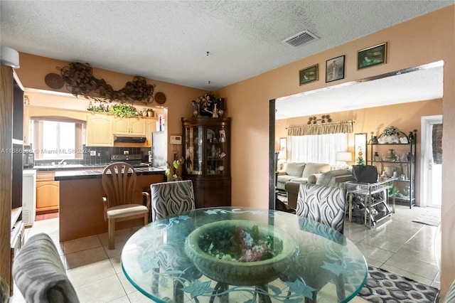 dining space with light tile patterned floors, a textured ceiling, and sink