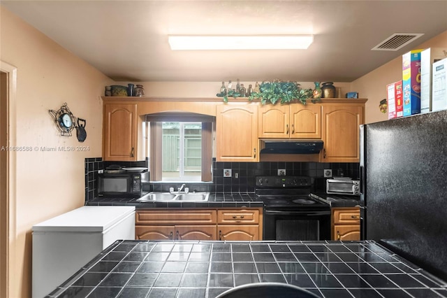 kitchen featuring backsplash, tile countertops, sink, and black appliances