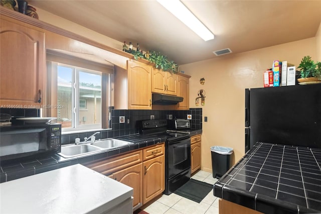 kitchen with backsplash, black appliances, sink, tile counters, and light tile patterned flooring