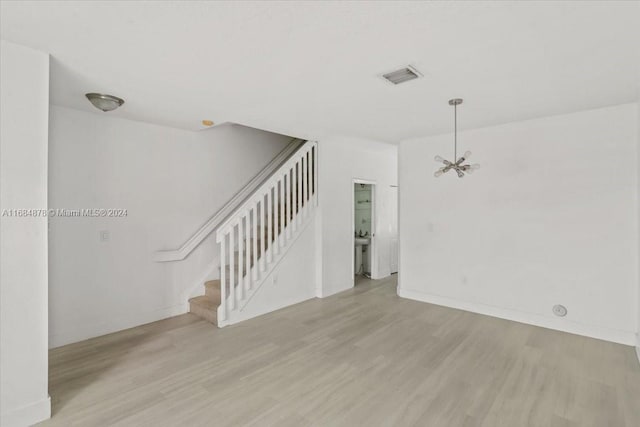 spare room with light hardwood / wood-style flooring and a notable chandelier