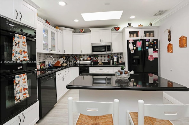 kitchen featuring sink, black appliances, white cabinetry, and backsplash