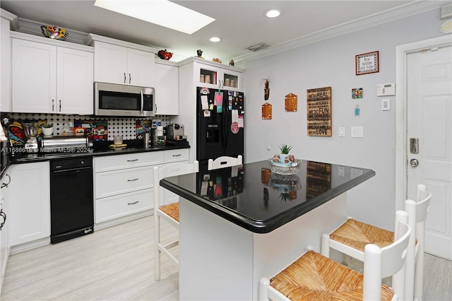 kitchen with decorative backsplash, a breakfast bar, white cabinets, and black fridge