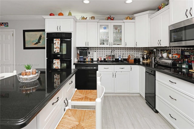 kitchen featuring decorative backsplash, white cabinets, black appliances, and sink