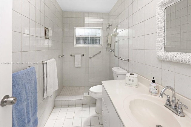 bathroom featuring a tile shower, toilet, tile walls, vanity, and tile patterned flooring