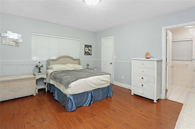 bedroom with radiator, ensuite bath, a textured ceiling, and dark hardwood / wood-style floors