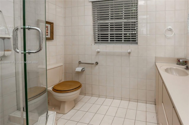 bathroom featuring a shower with door, toilet, tile patterned floors, tile walls, and vanity