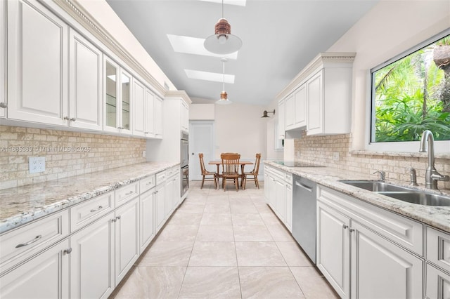 kitchen with a skylight, white cabinetry, sink, and stainless steel appliances