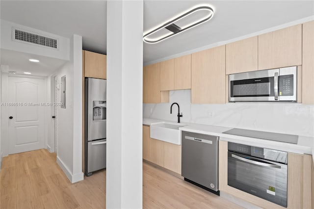 kitchen featuring sink, appliances with stainless steel finishes, light wood-type flooring, and light brown cabinets