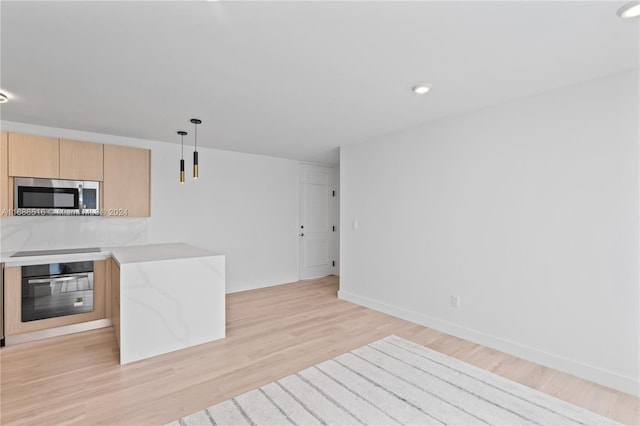 kitchen with light brown cabinets, hanging light fixtures, light stone counters, light hardwood / wood-style floors, and stainless steel appliances