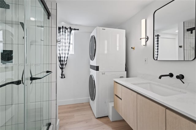 laundry area with sink, light wood-type flooring, and stacked washing maching and dryer