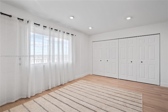 unfurnished bedroom with a closet and light wood-type flooring