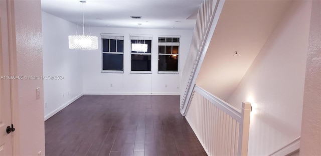 empty room with a chandelier and dark hardwood / wood-style flooring