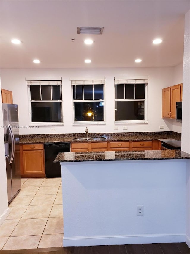 kitchen with black appliances, light tile patterned flooring, kitchen peninsula, and dark stone counters