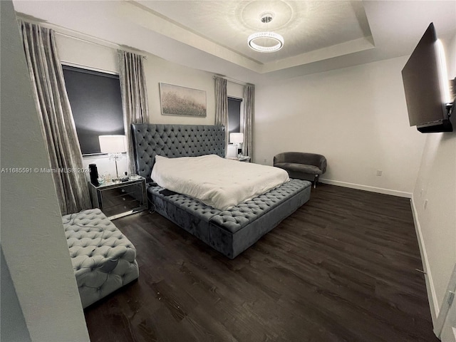 bedroom with dark wood-type flooring and a tray ceiling