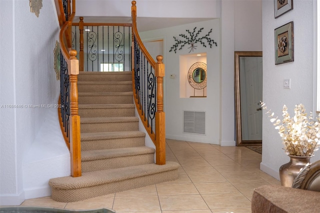 stairs with tile patterned floors and an inviting chandelier