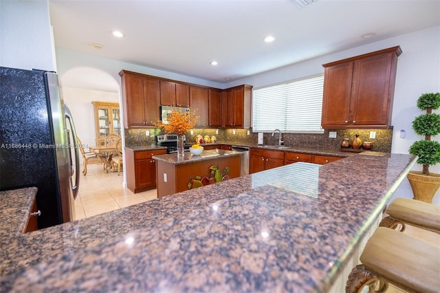 kitchen featuring appliances with stainless steel finishes, light tile patterned flooring, sink, a kitchen island, and a kitchen breakfast bar