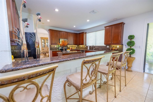 kitchen featuring kitchen peninsula, dark stone countertops, a healthy amount of sunlight, and stainless steel appliances