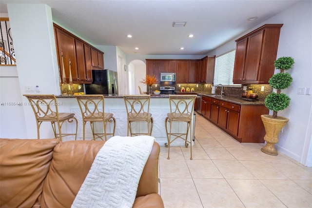 kitchen with dark stone countertops, appliances with stainless steel finishes, sink, and decorative backsplash