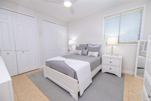 tiled bedroom with ceiling fan and multiple closets