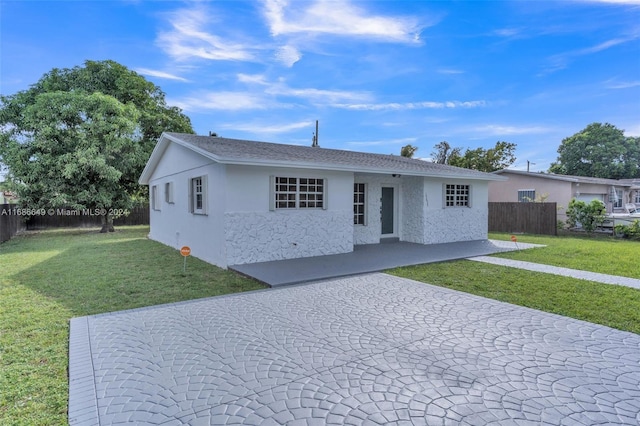 ranch-style home with a front lawn and a patio